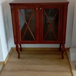 Ręcznie wykonana, drewniana witryna z przeszkleniami w kształcie rombów, na giętych nóżkach, ustawiona na panelach podłogowych. Klasyczny styl.