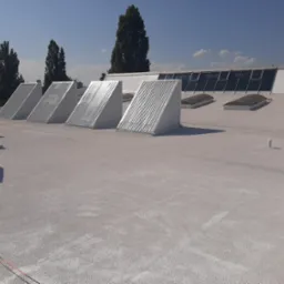 Biały dach przemysłowy po ociepleniu pianką PUR, widoczne kominki wentylacyjne, świetliki i klimatyzator na tle błękitnego nieba.