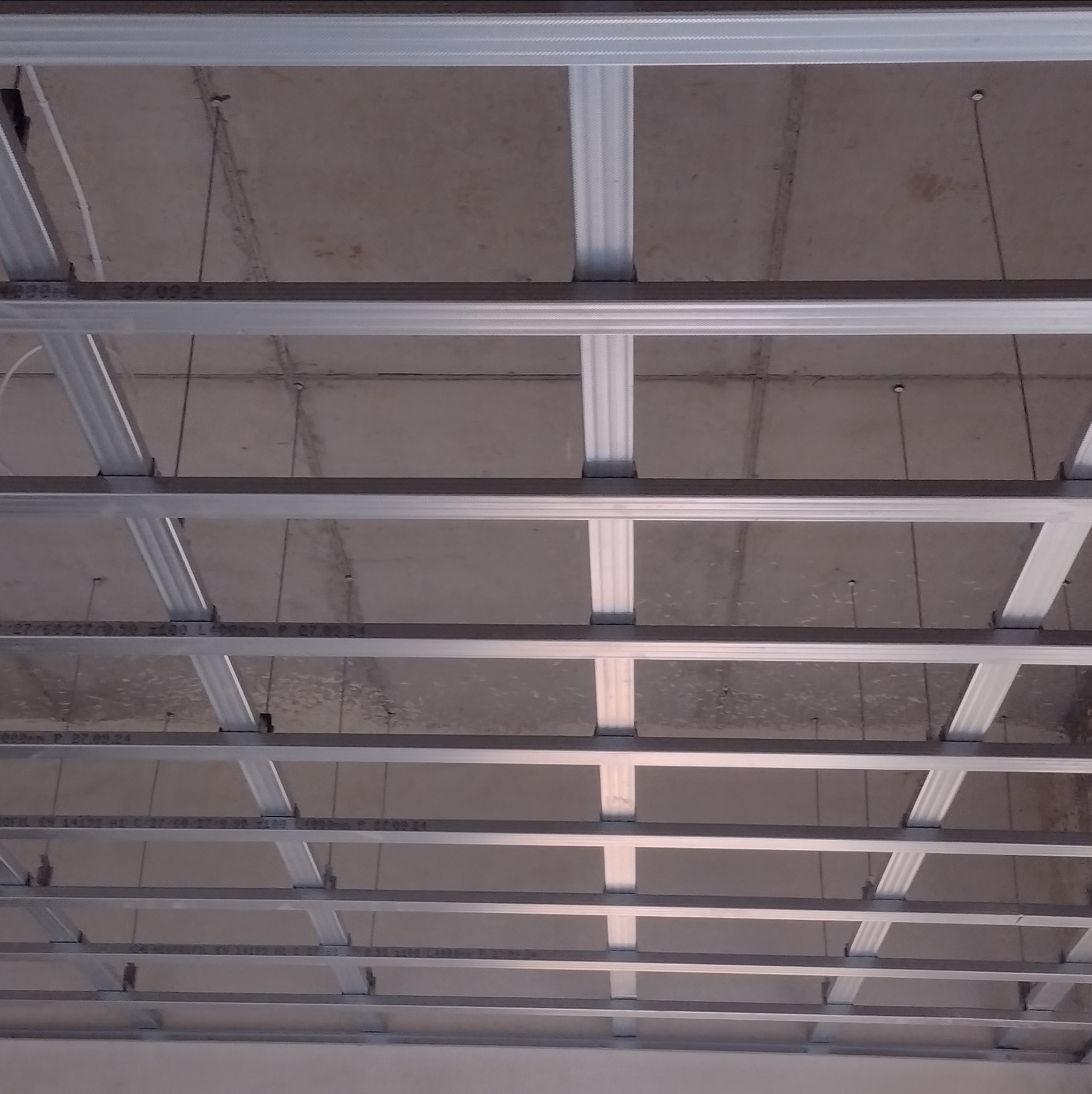 Metalowa konstrukcja sufitu podwieszanego z widocznym betonowym stropem, przygotowana do montażu płyt kartonowo-gipsowych.