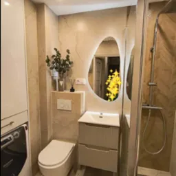 Nowoczesna łazienka z podświetlanym lustrem o nieregularnym kształcie, kabiną prysznicową typu walk-in z drewnopodobnymi płytkami ułożonymi w jodełkę, wiszącą toaletą i pralką w zabudowie.