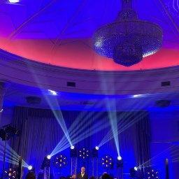 MOBILE STUDIO Rafał Solipiwko - Sala balowa z oświetleniem scenicznym, kryształowym żyrandolem i osobą na scenie w smokingu, widziana z perspektywy tłumu.