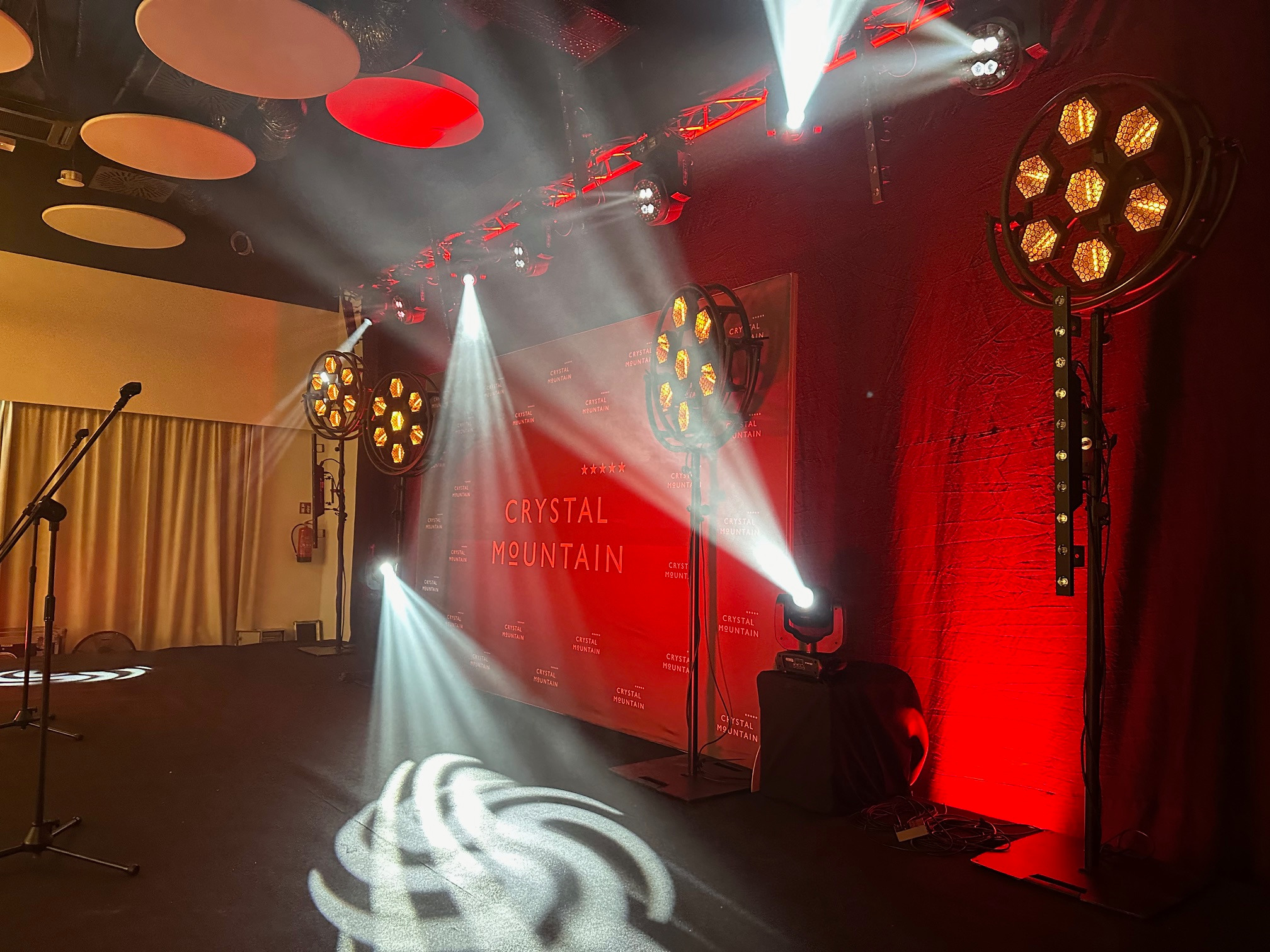 Scena oświetlona reflektorami, z banerem z napisem Crystal Mountain w tle i mikrofonami na statywach po lewej stronie.