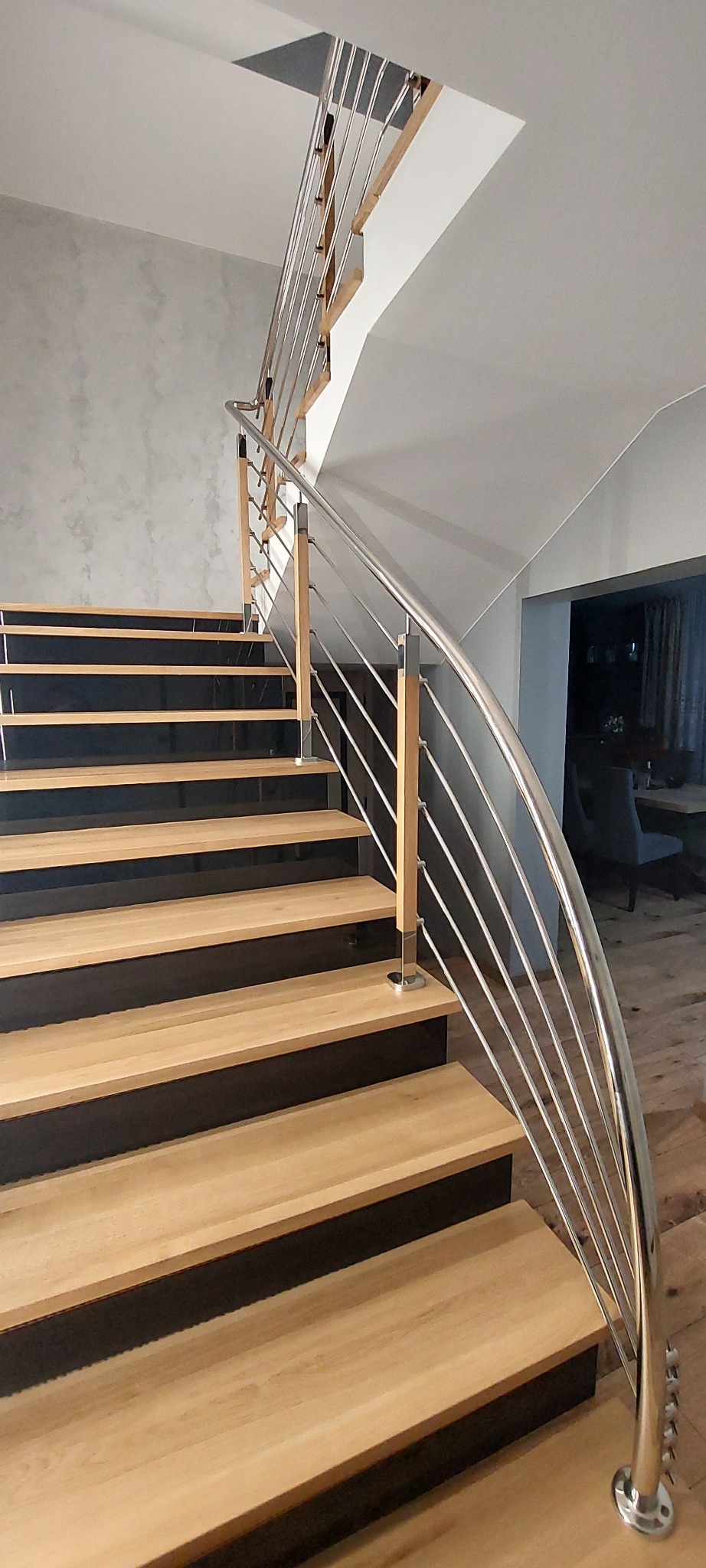 Schody z drewnianymi stopniami i balustradą z polerowanej stali nierdzewnej z drewnianymi słupkami, widok z dołu, nowoczesny design.