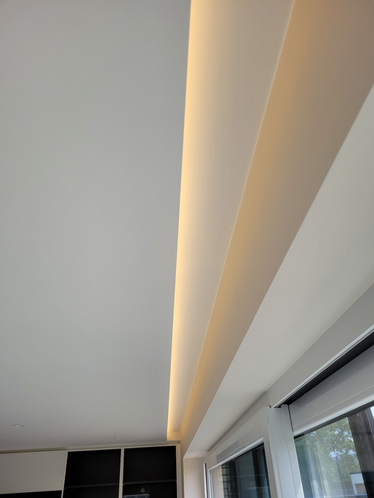 Ukryte oświetlenie LED w podwieszanym suficie w Nowej Karczmie, widoczne okno i fragment zabudowy meblowej.