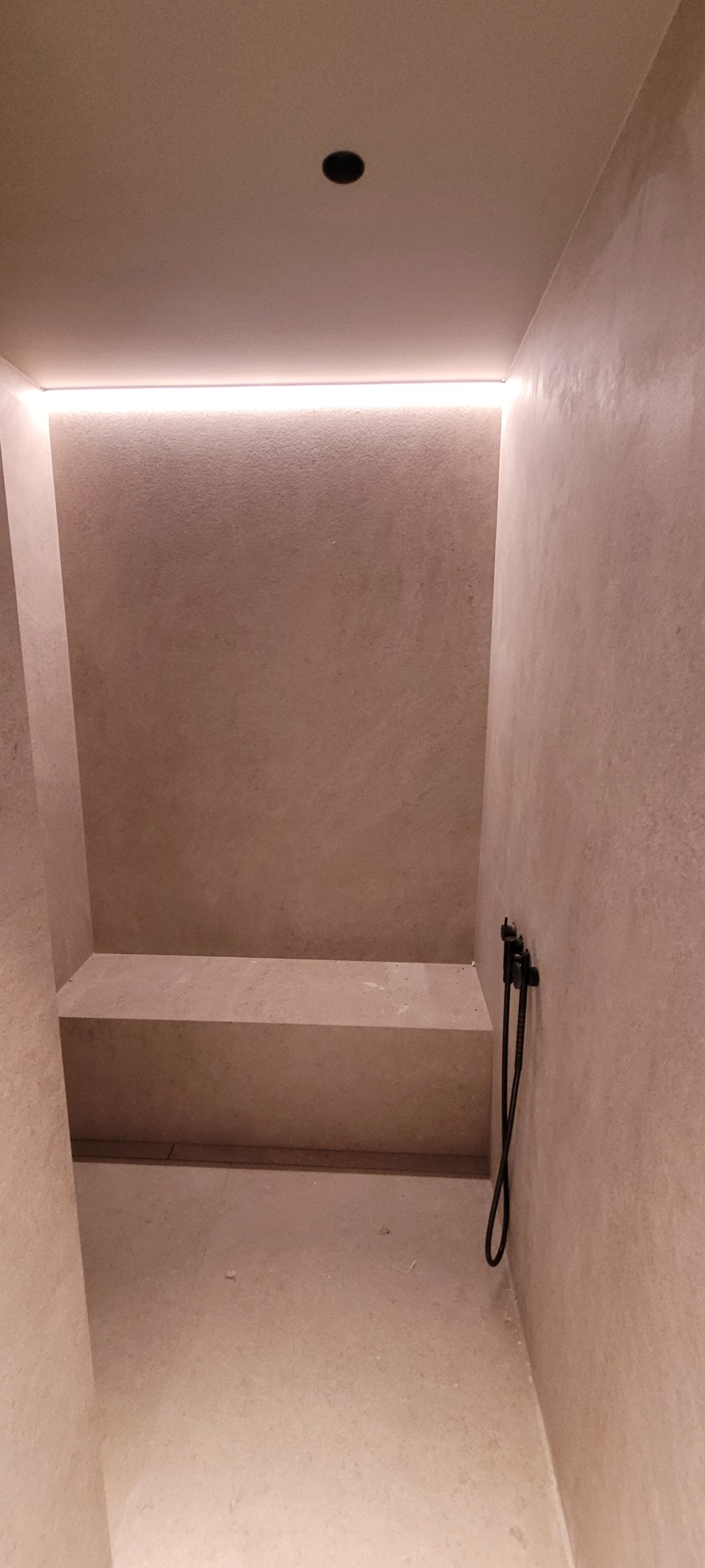 Minimalistyczna kabina prysznicowa z wbudowanym siedziskiem, oświetleniem LED podsufitowym i armaturą w kolorze czarnym.