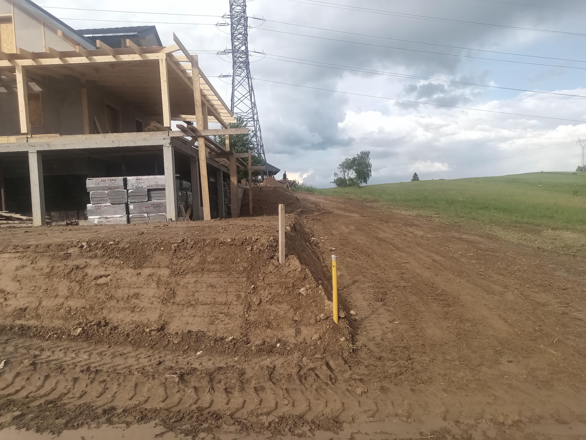 Budowa domu w Pieniążkowicach w trakcie wznoszenia fundamentów i konstrukcji szkieletowej. Widoczny wykop i ułożone materiały izolacyjne.