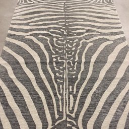 Sonia Świerlikowska - Nowoczesny dywan o wzorze inspirowanym skórą zebry, z centralnym motywem przypominającym kręgosłup, leżący na jasnej, gładkiej podłodze.