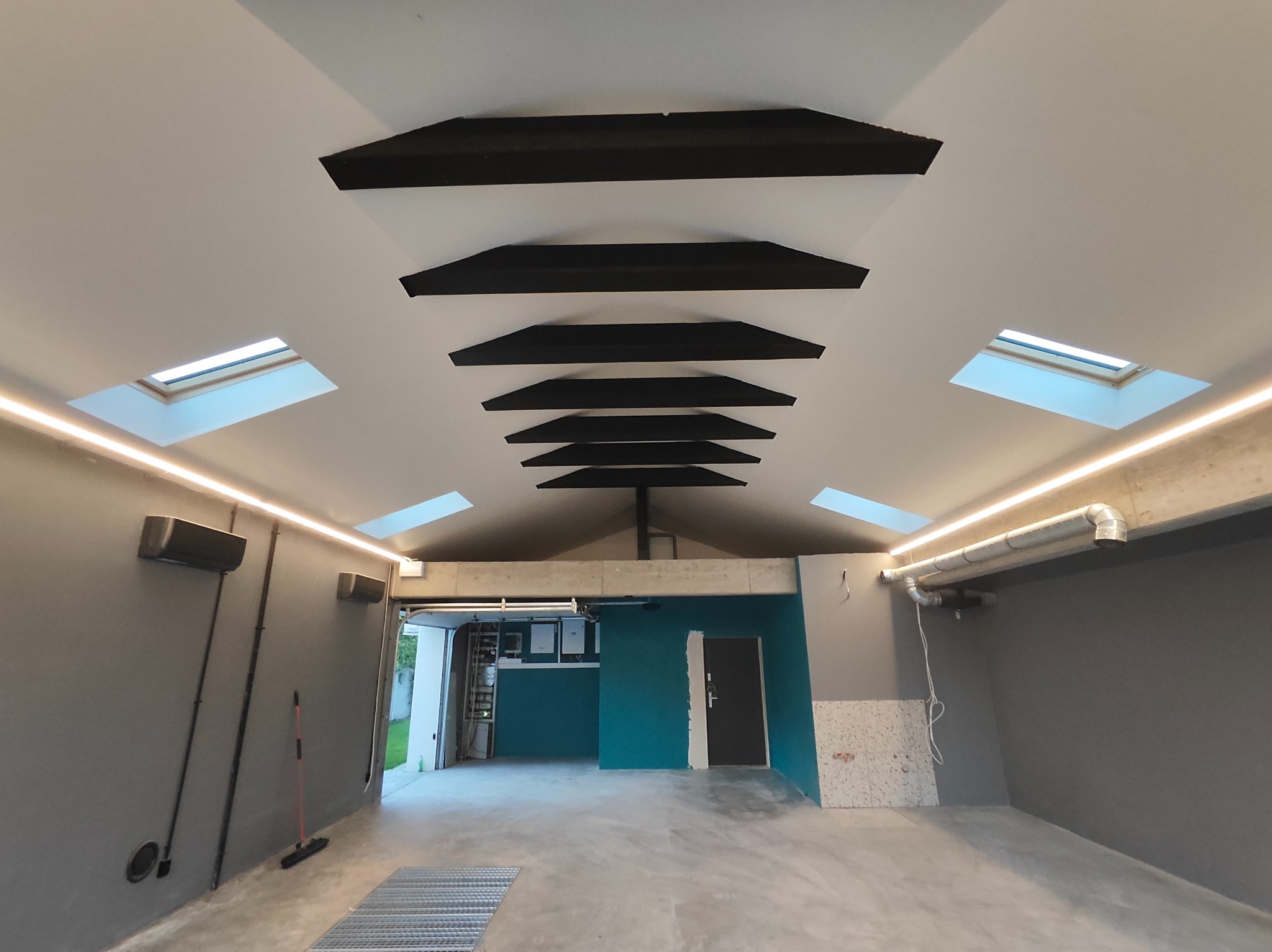 Szara łazienka z oknami dachowymi i czarnymi elementami dekoracyjnymi na suficie. Oświetlenie LED podkreśla nowoczesny charakter wnętrza.