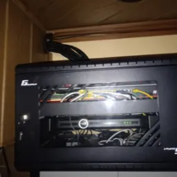 Czarna szafka rack zamontowana w szafce, widoczne kable i urządzenia sieciowe, oświetlenie LED wewnątrz, logo Geffort na obudowie.