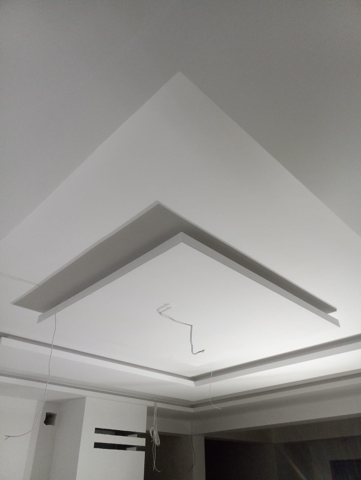 Wielopoziomowy sufit podwieszany z płyt kartonowo-gipsowych, widoczne przewody elektryczne przed montażem oświetlenia.