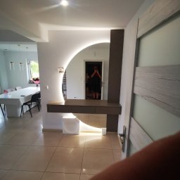 MK FURNITURE Michał Kalinowski - Nowoczesna toaletka z podświetlanym, okrągłym lustrem i szufladami, zrealizowana w Łomży, widoczna na tle jadalni z długim stołem i krzesłami.