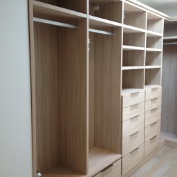 Wysmeble - Jasna, drewnopodobna garderoba z szufladami i półkami, widoczna puszka z preparatem do pielęgnacji drewna, częściowo pusta.