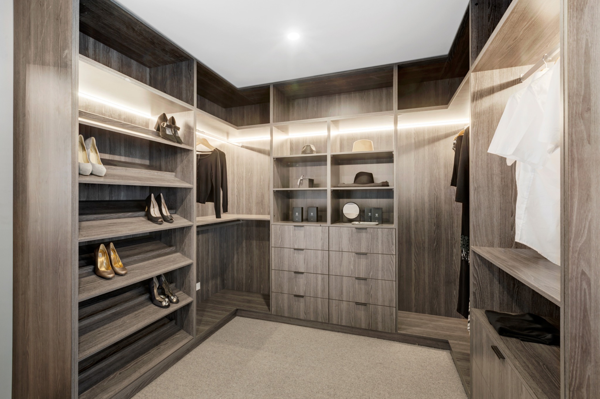 Przestronna garderoba w odcieniach szarości z oświetleniem LED, półkami na buty i ubrania oraz komodą z szufladami.