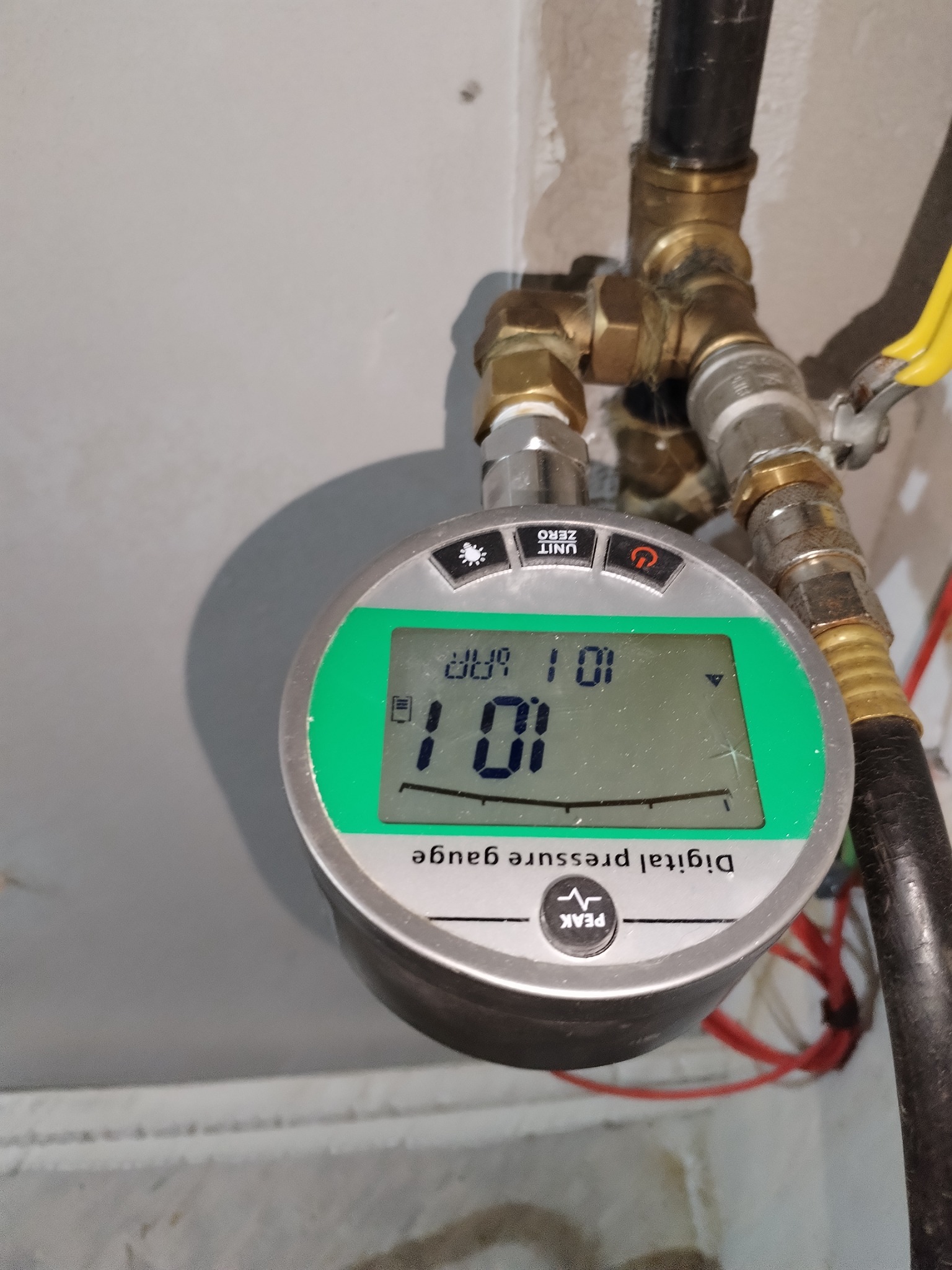 Cyfrowy manometr podłączony do instalacji gazowej z widocznym wskazaniem ciśnienia na wyświetlaczu.