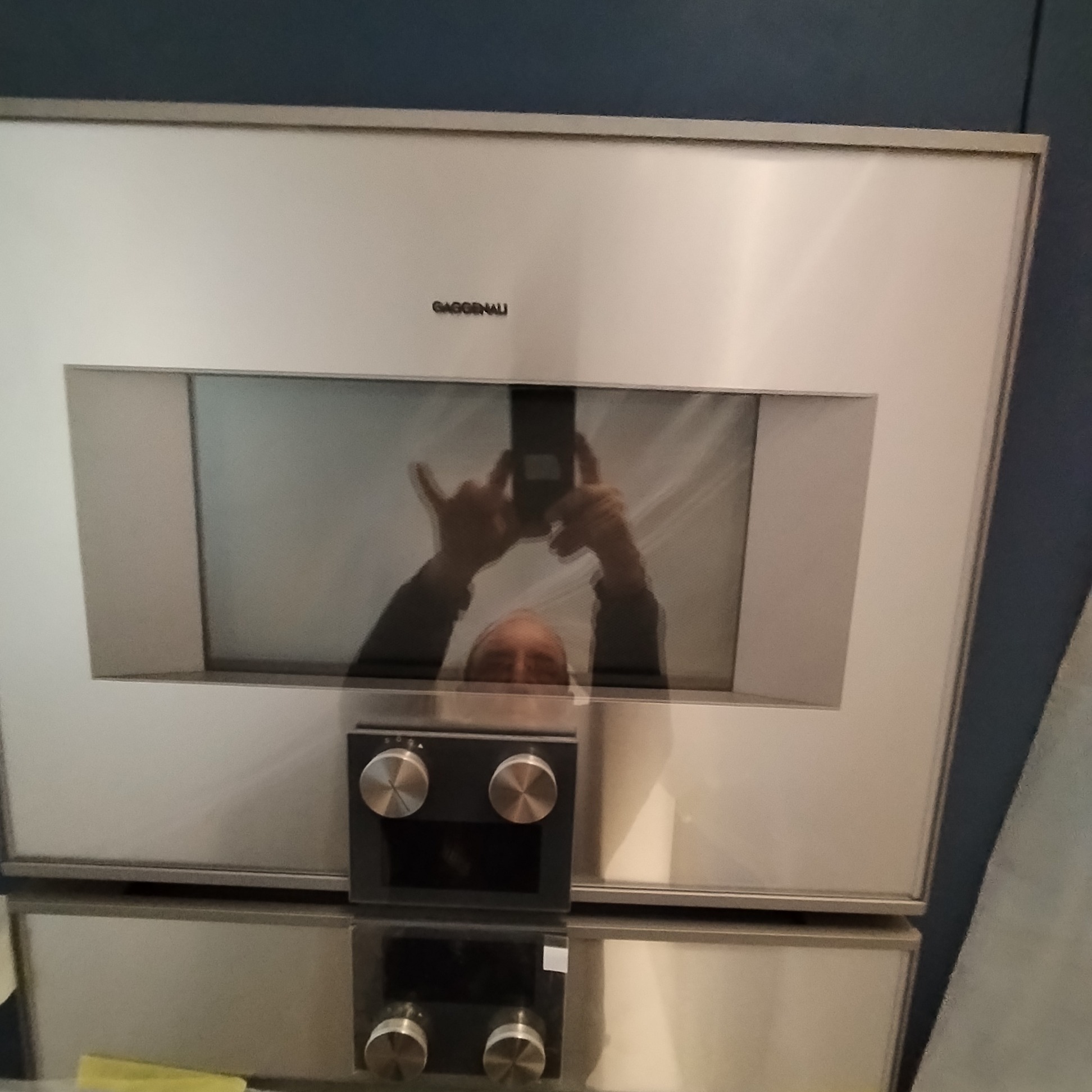 Wbudowany piekarnik gazowy marki Gaggenau z odbiciem osoby robiącej zdjęcie telefonem.