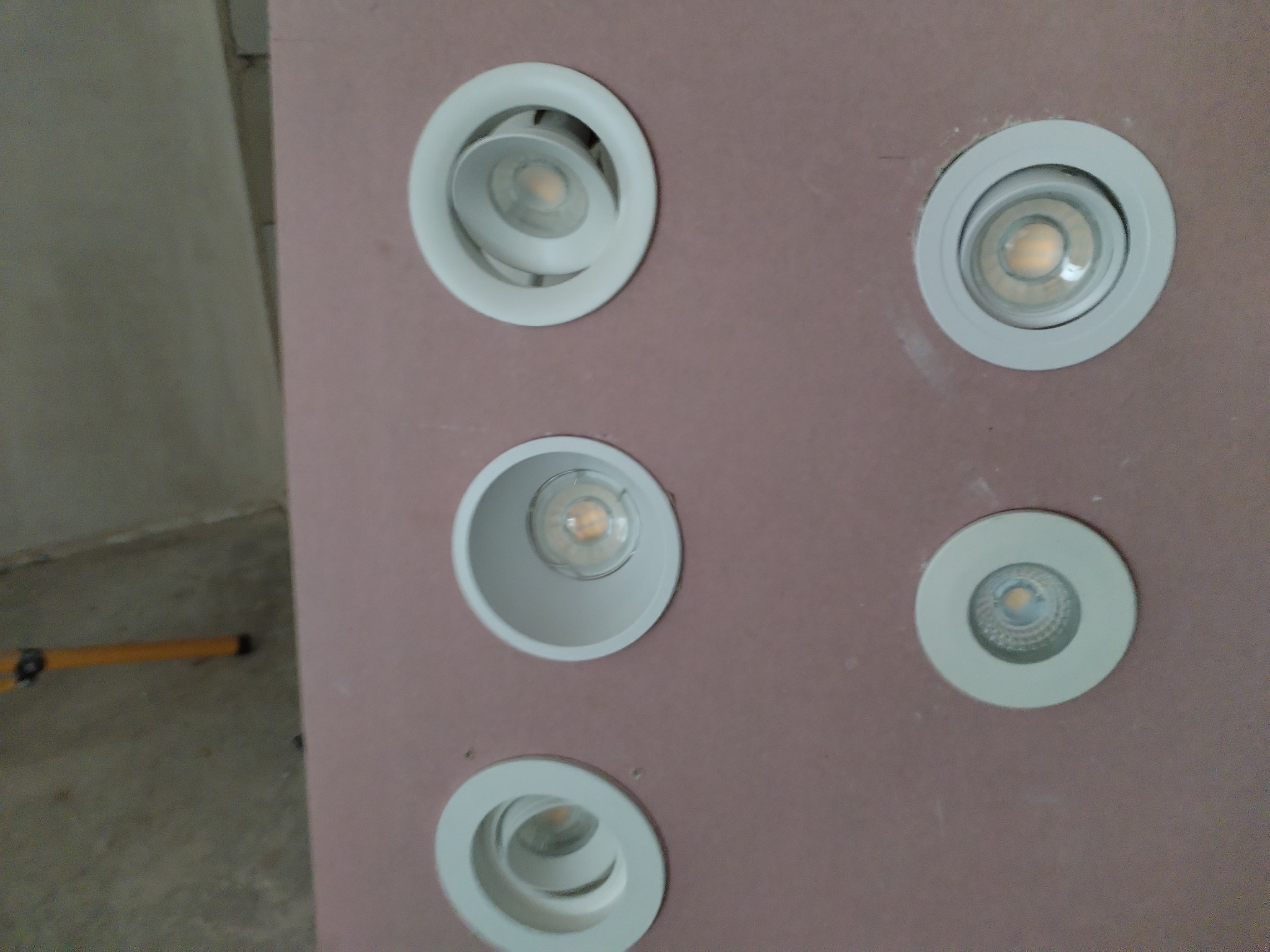 Zamontowane, okrągłe, białe oprawy oświetleniowe LED w suficie podwieszanym z płyt kartonowo-gipsowych, widok z bliska na tle wnętrza w Gdyni.