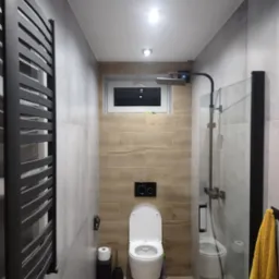 Nowoczesna łazienka z szarymi i drewnopodobnymi płytkami, czarną armaturą, grzejnikiem drabinkowym i kabiną prysznicową typu walk-in.