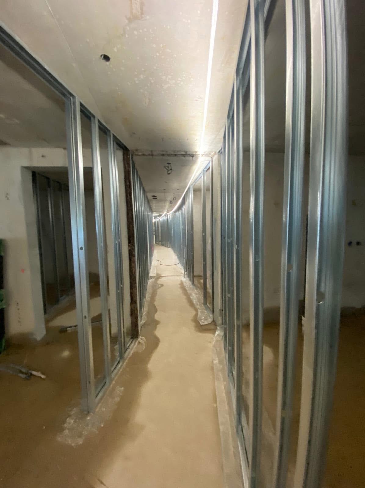 Montaż metalowej konstrukcji szkieletowej pod płyty karton gips w korytarzu w Krasnymstawie, widoczne profile pionowe i izolacja w niektórych miejscach.