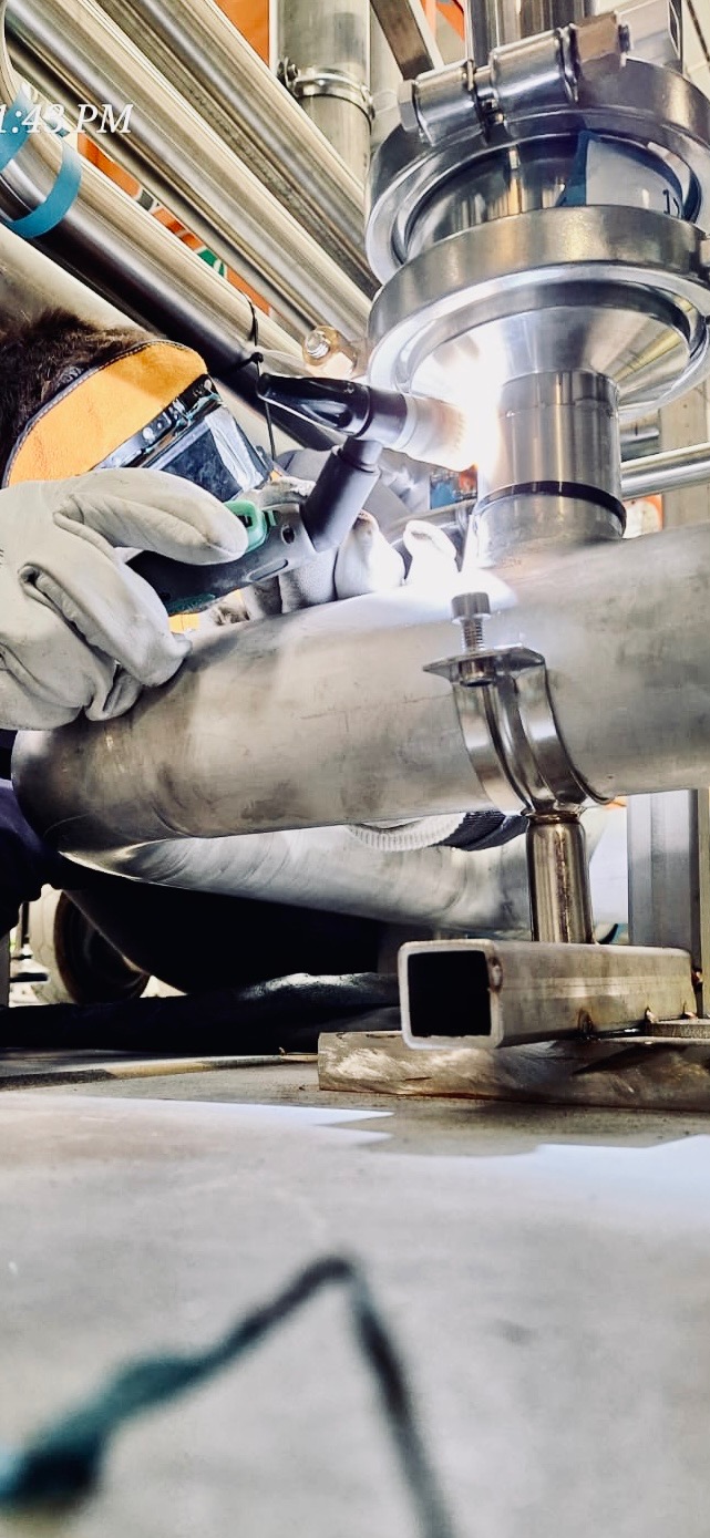 Spawanie rury ze stali nierdzewnej z użyciem spawarki TIG, widoczne iskry i osłona spawalnicza.