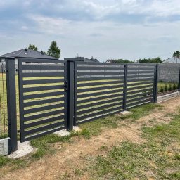 Marbruk - Nowoczesna, pozioma brama i przęsła ogrodzeniowe w kolorze grafitowym, z widocznym zamknięciem, na tle trawnika i domu jednorodzinnego.