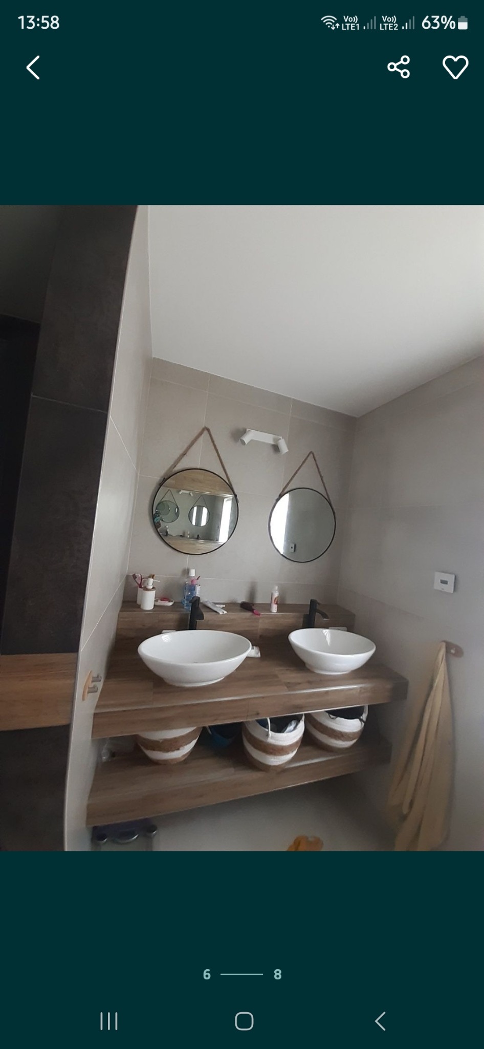 Nowoczesna łazienka z podwójną umywalką nablatową, drewnianym blatem i okrągłymi lustrami zawieszonymi na sznurkach, uzupełniona o białe kosze pod blatem.