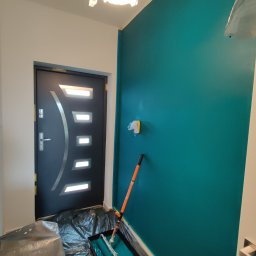 Andrzej Grab - Ściana w odcieniu turkusu, świeżo pomalowana, z wałkiem i kuwetą na folii ochronnej, widoczna nowoczesna czarna stolarka drzwiowa z metalową aplikacją.