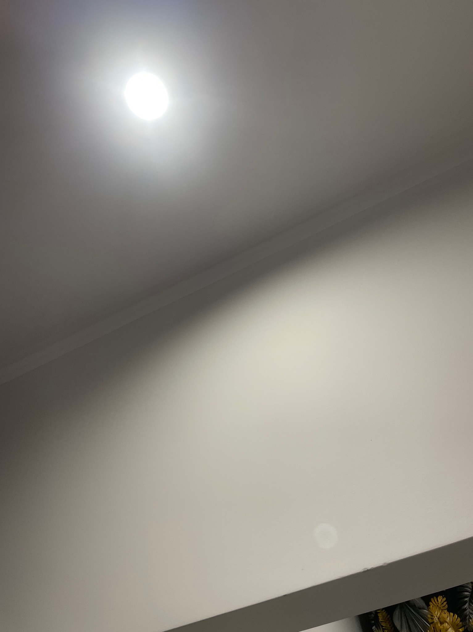 Biały sufit z listwą przysufitową i punktowym oświetleniem, widoczne delikatne niedoskonałości powierzchni.