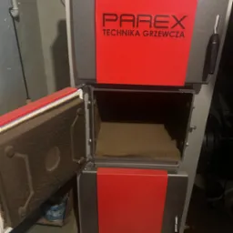 Otwarty piec na paliwo stałe Parex Technika Grzewcza z widocznym wnętrzem paleniska, zainstalowany w kotłowni w Warszawie.