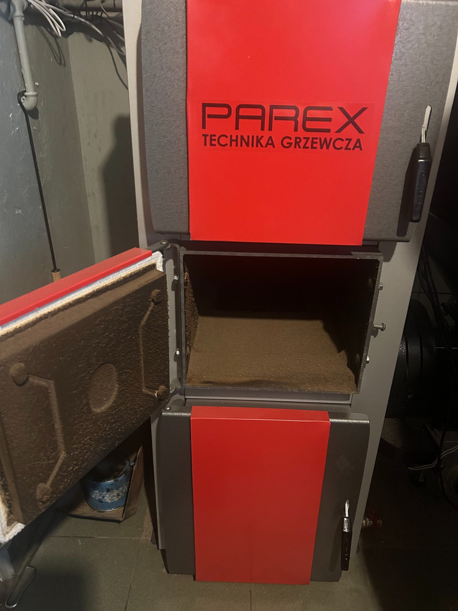 Otwarty piec na paliwo stałe Parex Technika Grzewcza z widocznym wnętrzem paleniska, zainstalowany w kotłowni w Warszawie.