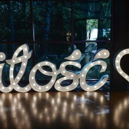 FOTOFRAJDA ALEKSANDRA MICEK - Świecący napis 'Miłość' i serce z żarówkami jako dekoracja sali weselnej, widok z niskiej perspektywy.