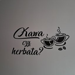 Mateusz nie - Czarny naklejany napis na szarej ścianie: 'Kawa czy herbata?', z grafiką filiżanek i ziaren kawy.