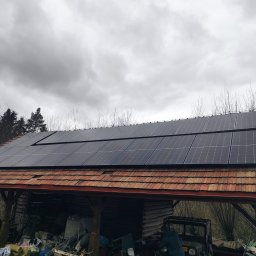 D&D Instal - Panele słoneczne na dachu wiaty z czerwoną dachówką, pochmurne niebo w tle.