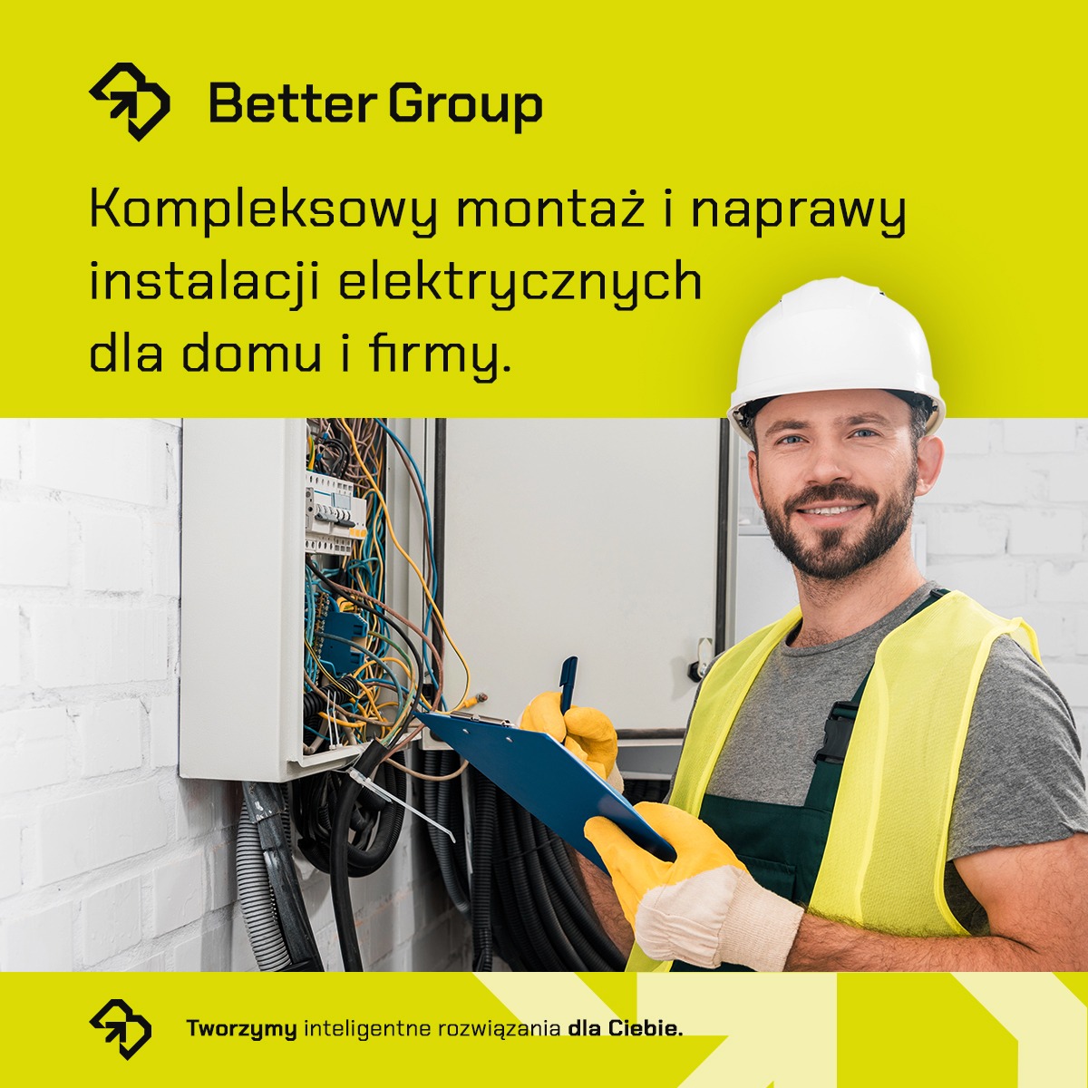 Elektryk w kasku i kamizelce odblaskowej, uśmiechnięty, sprawdza skrzynkę z bezpiecznikami, trzymając w ręku niebieski clipboard. Widoczne kable i przewody. Tło to biała ściana z cegieł.