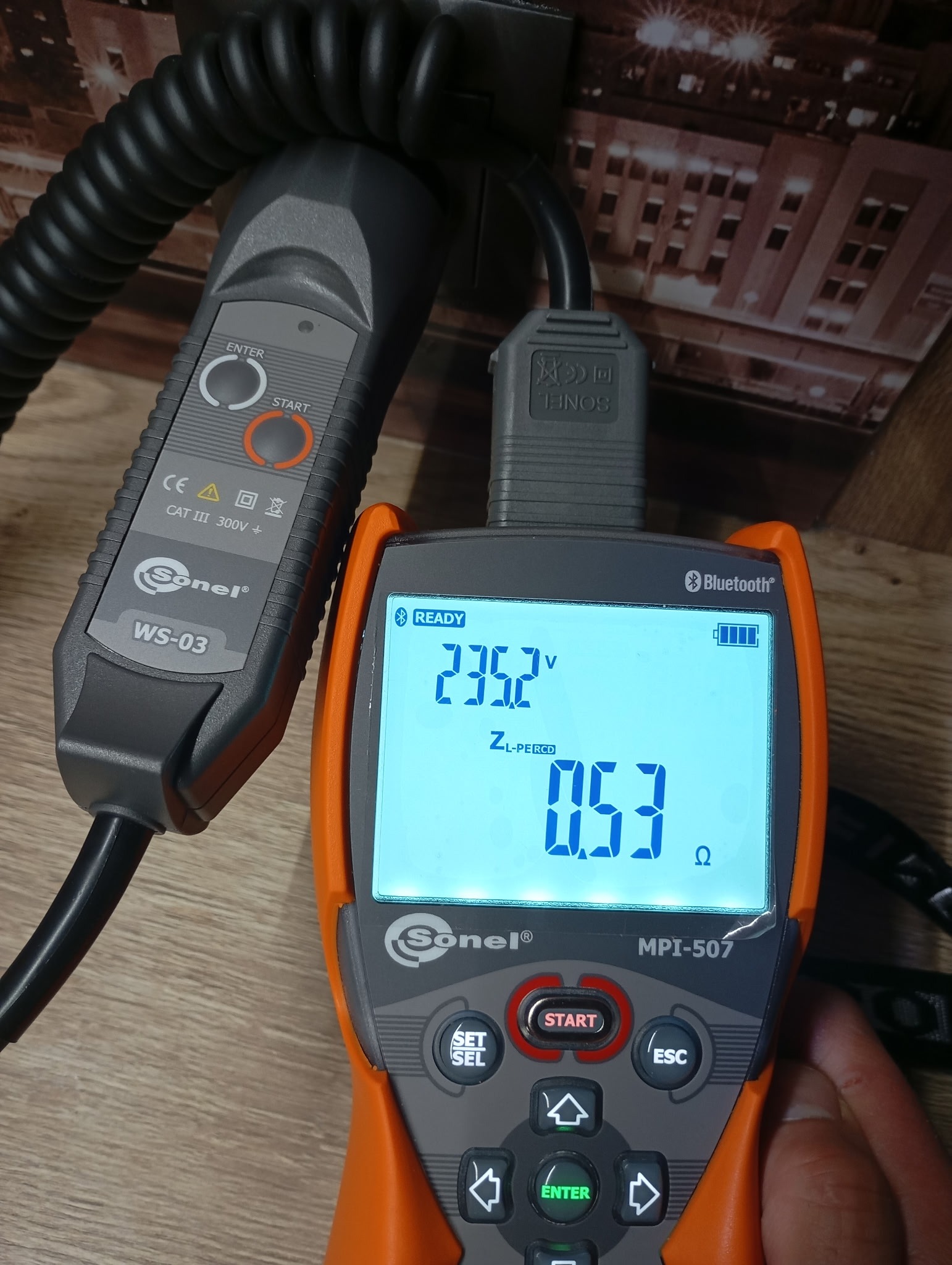 Miernik Sonel MPI-507 z wyświetlanymi wartościami napięcia 235.2V i impedancji 0.53Ω, używany do pomiarów elektrycznych. Widoczny przewód pomiarowy WS-03.