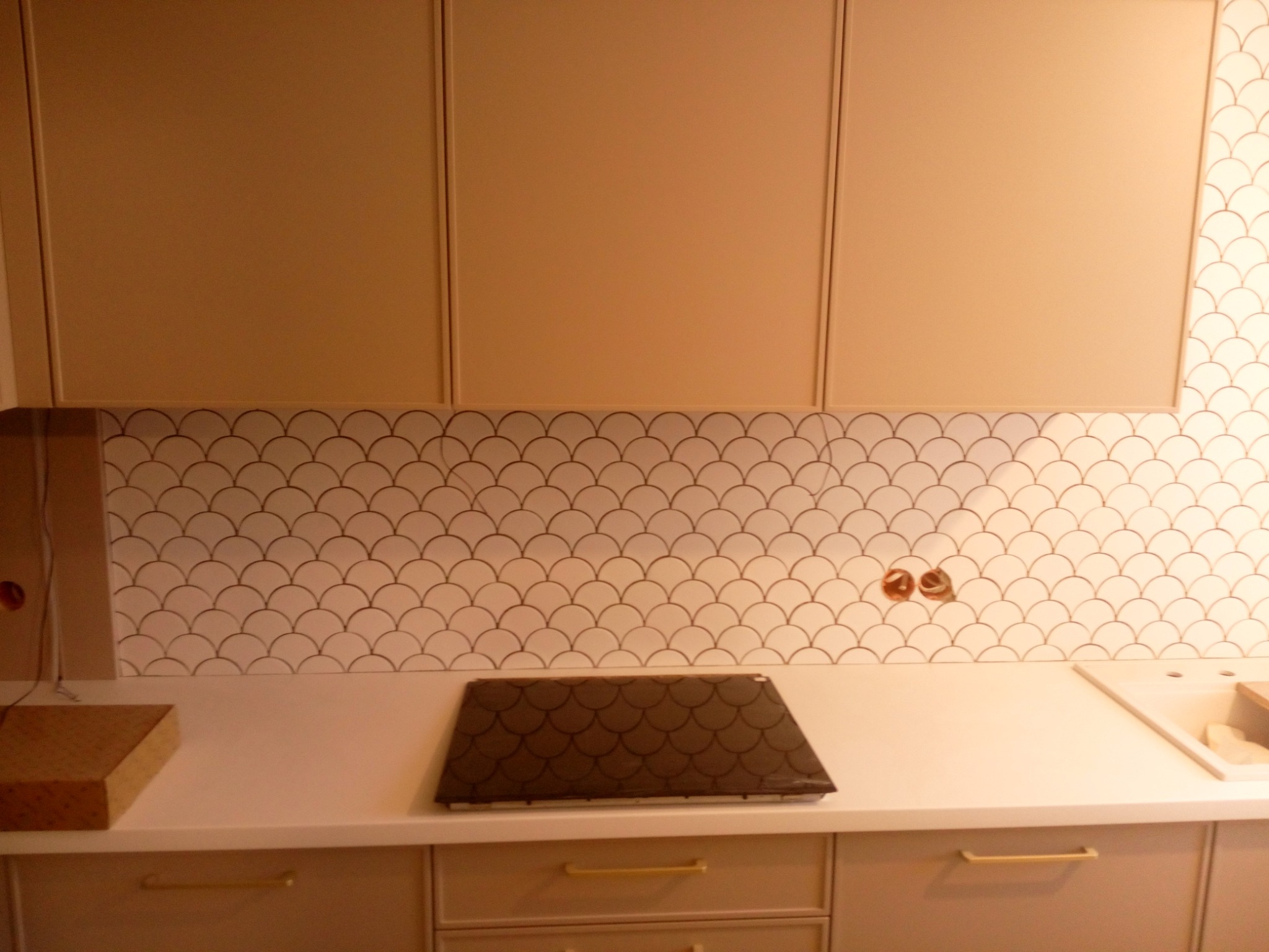 Kuchnia w Gliwicach z blatem i płytkami w kształcie rybiej łuski. Widoczne gniazdka elektryczne przed montażem osprzętu.