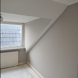 Polstal-Artur Bernekier - Pomalowane na szaro poddasze z oknem, grzejnikiem i zabezpieczonymi listwami przypodłogowymi przed malowaniem.