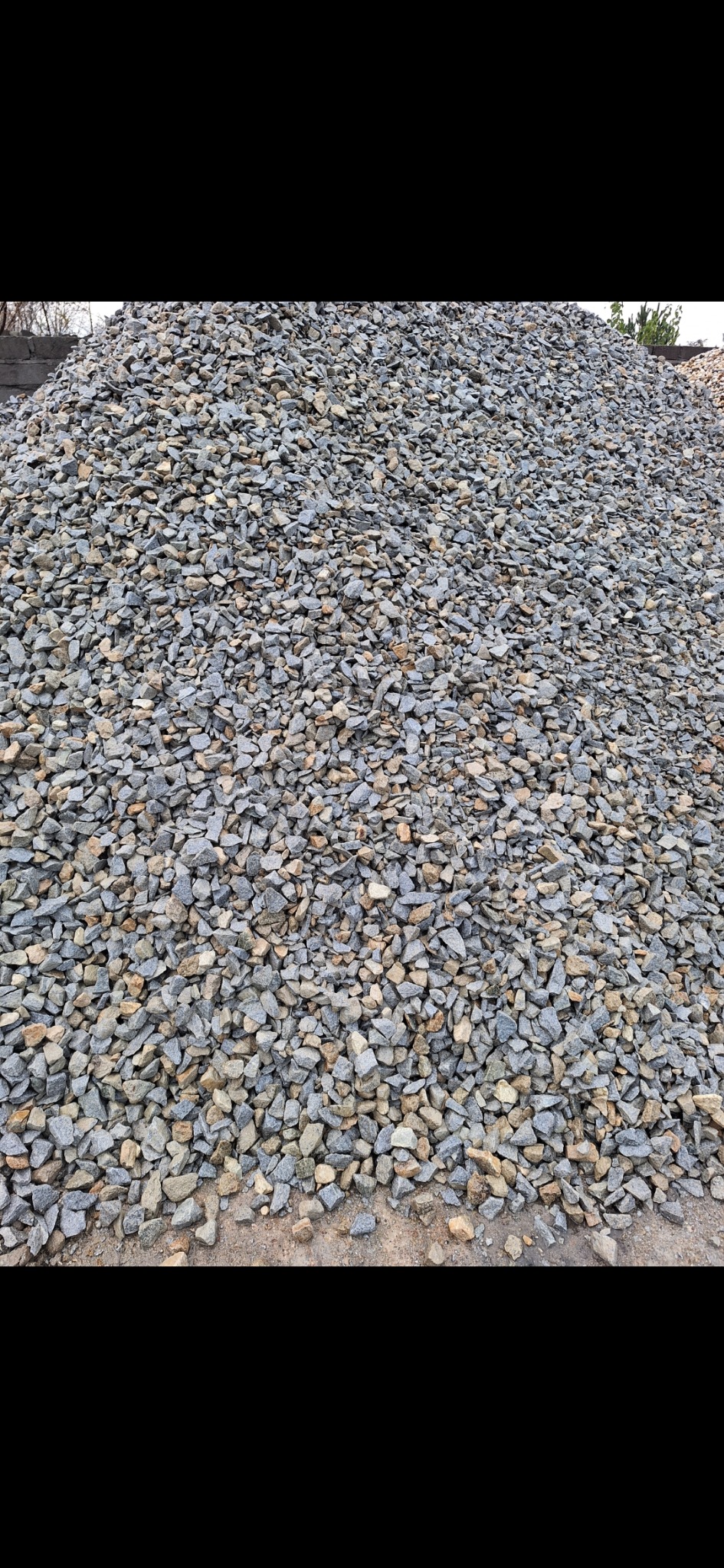 Kupa szarego i beżowego kruszywa o ostrych krawędziach, ułożona na ziemi, widoczna tekstura poszczególnych kamieni.