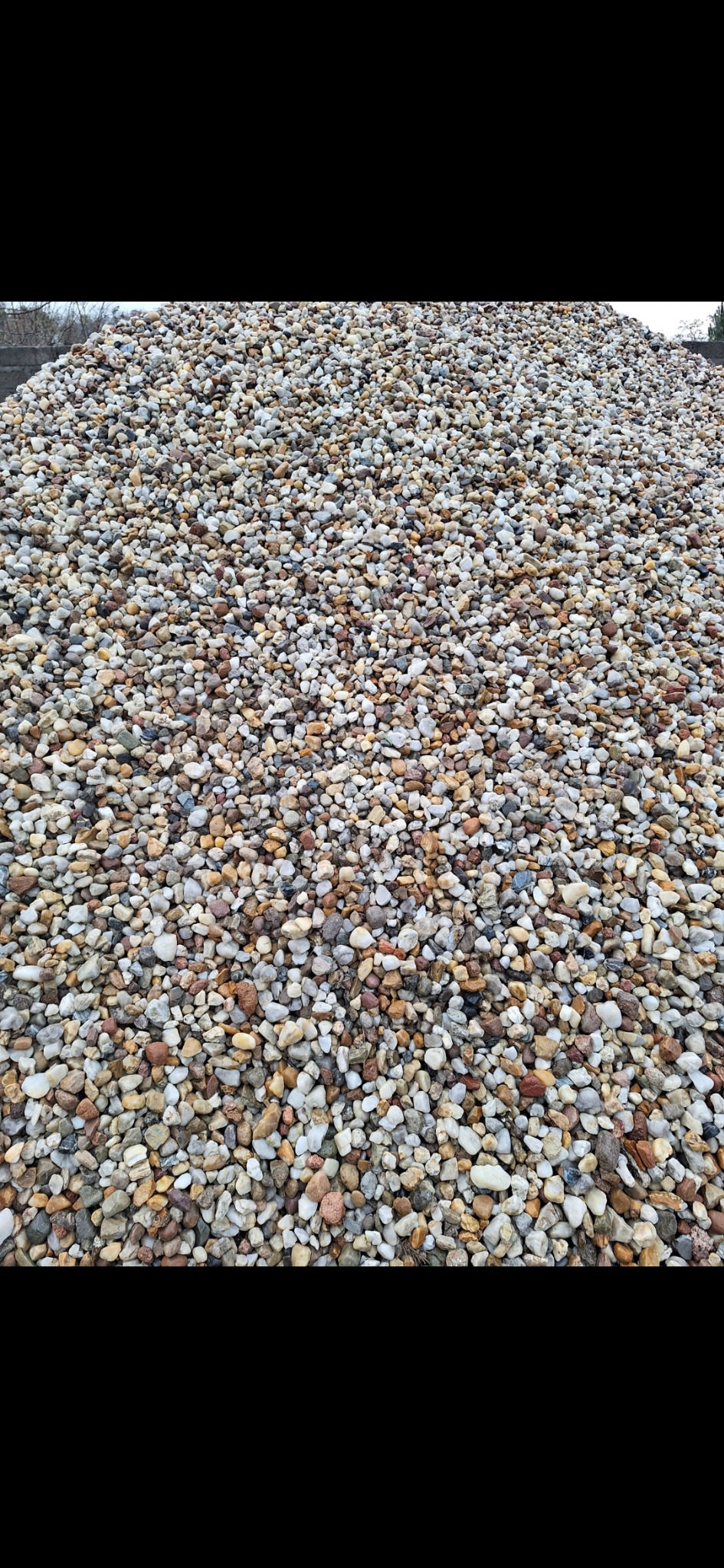 Góra drobnych, okrągłych kamieni w odcieniach bieli, beżu i brązu, tworząca dużą pryzmę na zewnątrz.