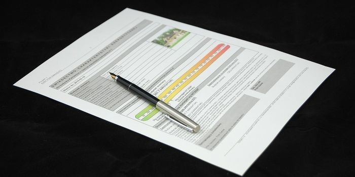 Świadectwo charakterystyki energetycznej budynku leżące na czarnym tle, z piórem wiecznym obok, wskazujące na klasę energetyczną budynku.