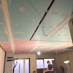 KW PRO-BUD - Sufit w trakcie montażu płyt karton-gips, widoczne łączenia i otwór na oświetlenie, dwóch mężczyzn w pomieszczeniu.