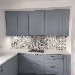 Lamit-Meble Jacek Andrzejczyk - Niebieska zabudowa kuchenna z marmurowym blatem i dekoracyjnymi płytkami nad indukcją. Klasyczny styl, srebrne uchwyty, jasne drewno na podłodze.