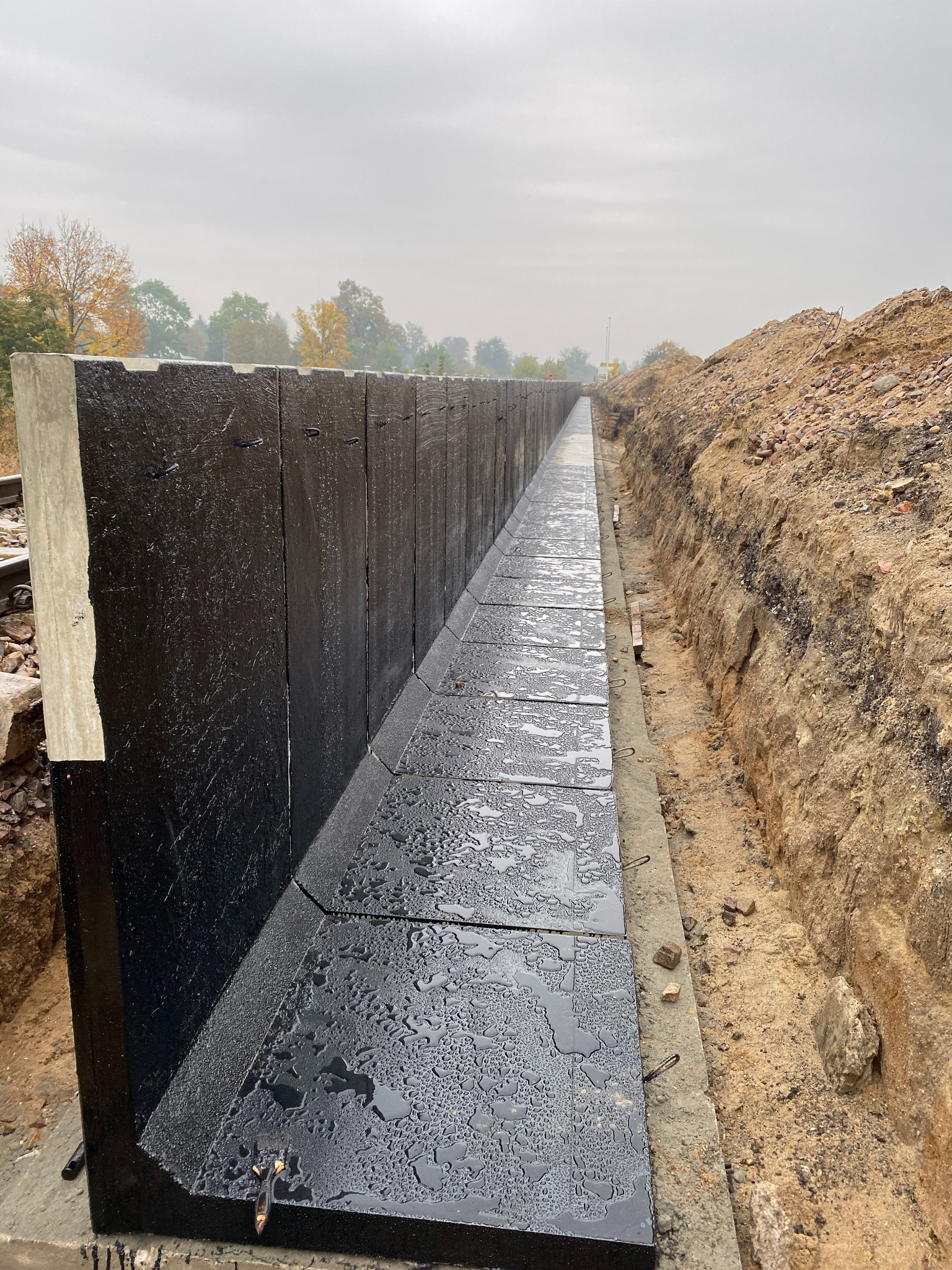 Budowa drenażu liniowego z prefabrykatów betonowych, zabezpieczonych hydroizolacją, w wykopie ziemnym.