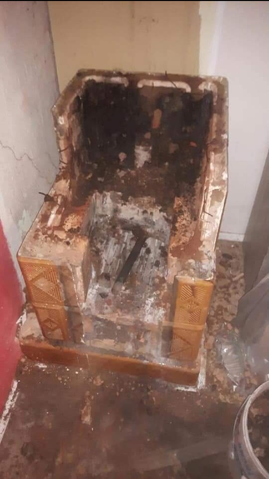 Zdemontowany, zabrudzony piec kaflowy w trakcie prac. Widoczne pozostałości po demontażu i zabrudzenia na podłodze. Detal z bliska.