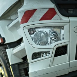 HDD-WANDES SPÓŁKA Z OGRANICZONĄ ODPOWIEDZIALNOŚCIĄ - Fragment białej ciężarówki z widocznym reflektorem i odblaskowymi pasami ostrzegawczymi.