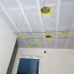GLANZ - Przygotowanie do malowania: sufit i ściany zabezpieczone folią ochronną z taśmą, widoczne otwory na oświetlenie. Okno z PCV. Prace wykończeniowe w trakcie.