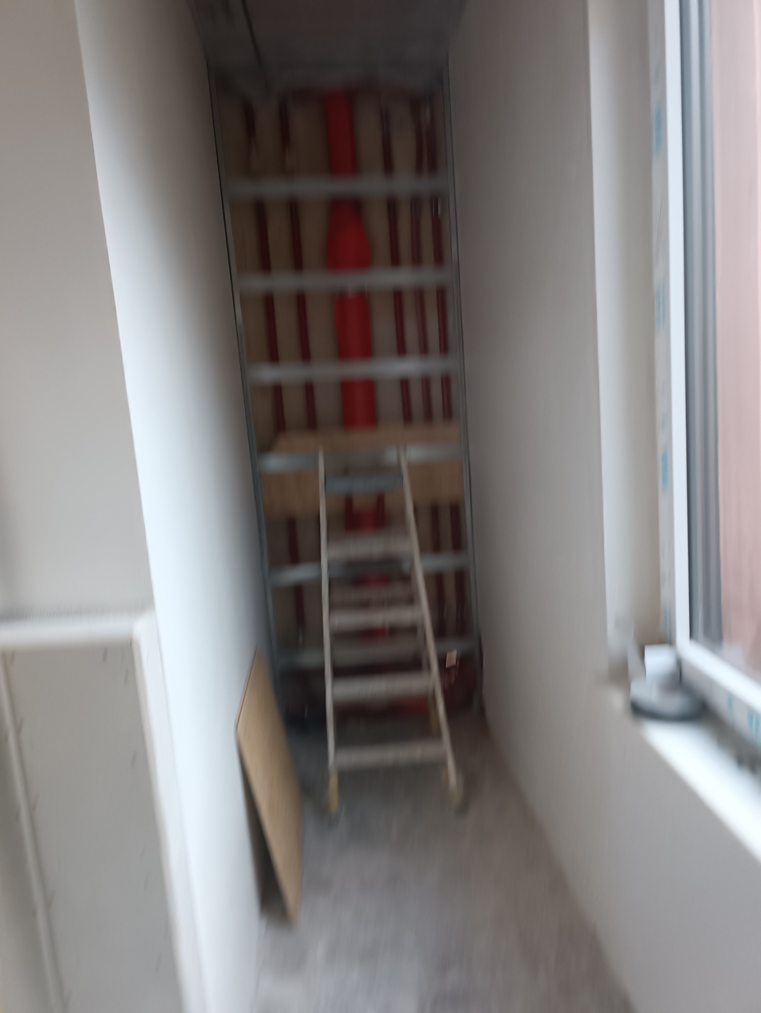 Wnętrze w trakcie prac: metalowy stelaż pod zabudowę, widoczne instalacje, drabina oparta o ścianę, płyta gipsowa. Przygotowanie do wykończenia.