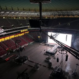 btone.tech sp. z o.o. - Przygotowania do koncertu na stadionie: widok z góry na scenę, nagłośnienie i oświetlenie w trakcie montażu, z widocznymi elementami konstrukcyjnymi i pustymi trybunami
