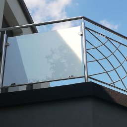BAR ANDRZEJ ANDRZBAR - Balkon z nowoczesną balustradą ze stali nierdzewnej z wypełnieniem szklanym i ażurowym metalowym, widok z dołu na tle błękitnego nieba.