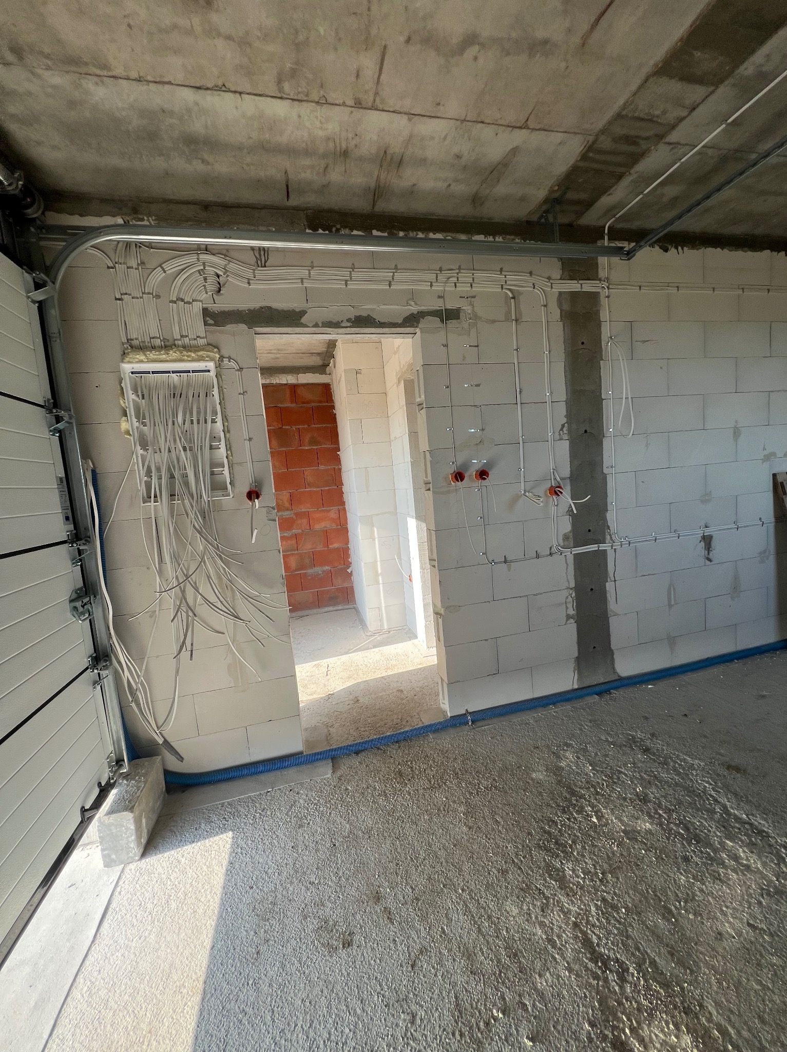 Rozprowadzenie przewodów elektrycznych w surowym budynku z białego betonu komórkowego w Rębiskach. Widoczne puszki i kable.