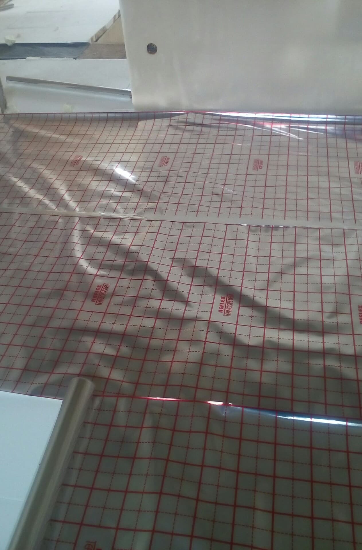 Mata grzewcza z nadrukowaną czerwoną siatką na podłodze, widoczne oznaczenia producenta Reflex Termosystem.